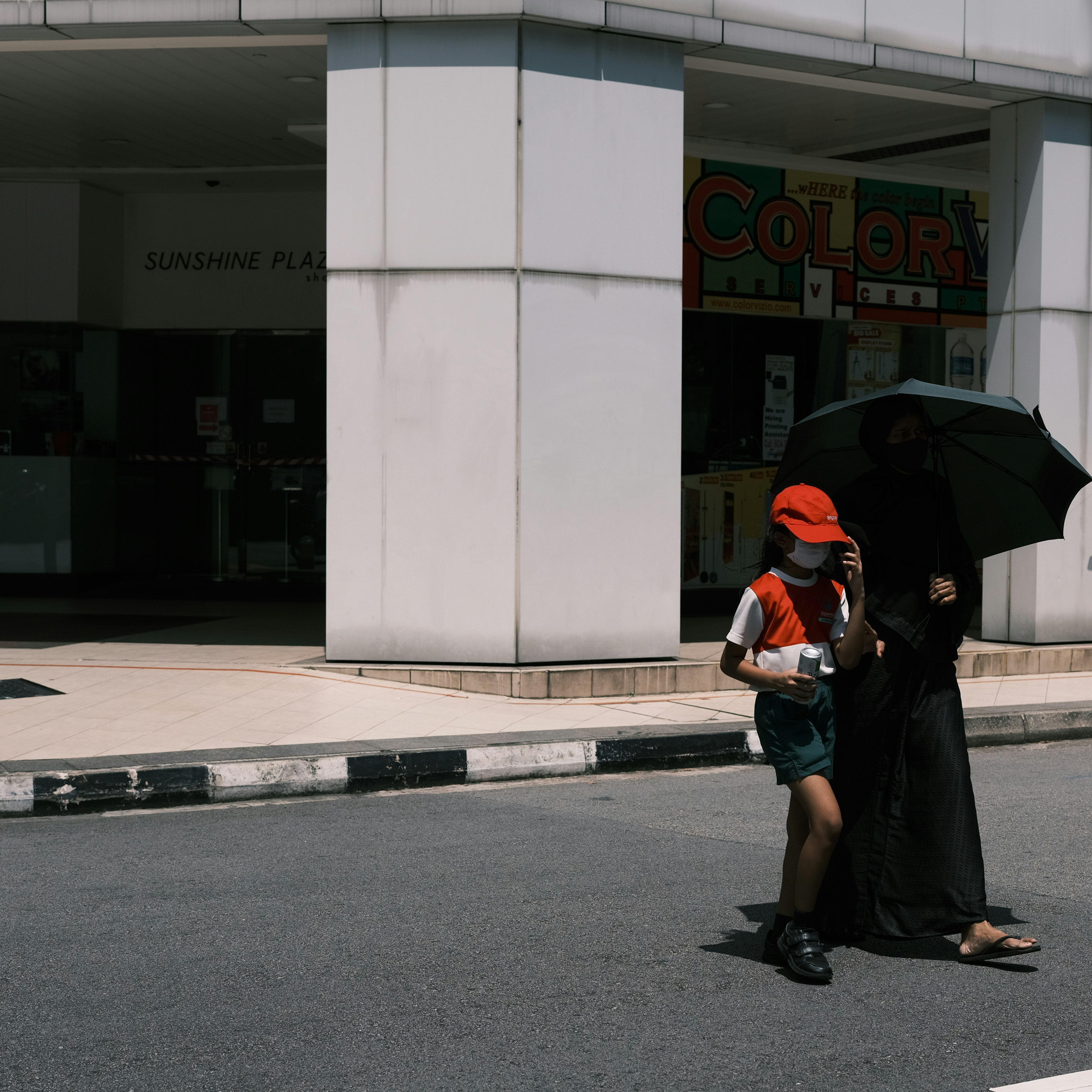 woman in black jacket and black skirt holding umbrella walking on sidewalk during daytime